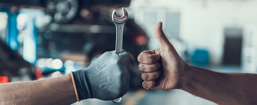 Two men doing thumbs up one using a wrench 